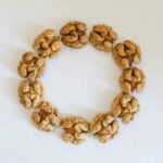 Top view of walnuts arranged in a circle on a white background, showcasing texture.
