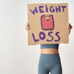 Person holding 'weight loss' sign for fitness motivation and health goals.