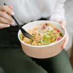 Close-up of a woman eating a fresh salad outdoors, exuding healthy and casual vibes.